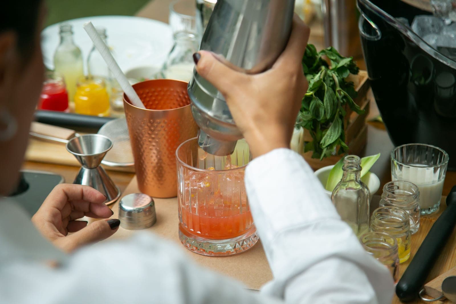 A home bar mid-build with bottles, tools and a mixing glass