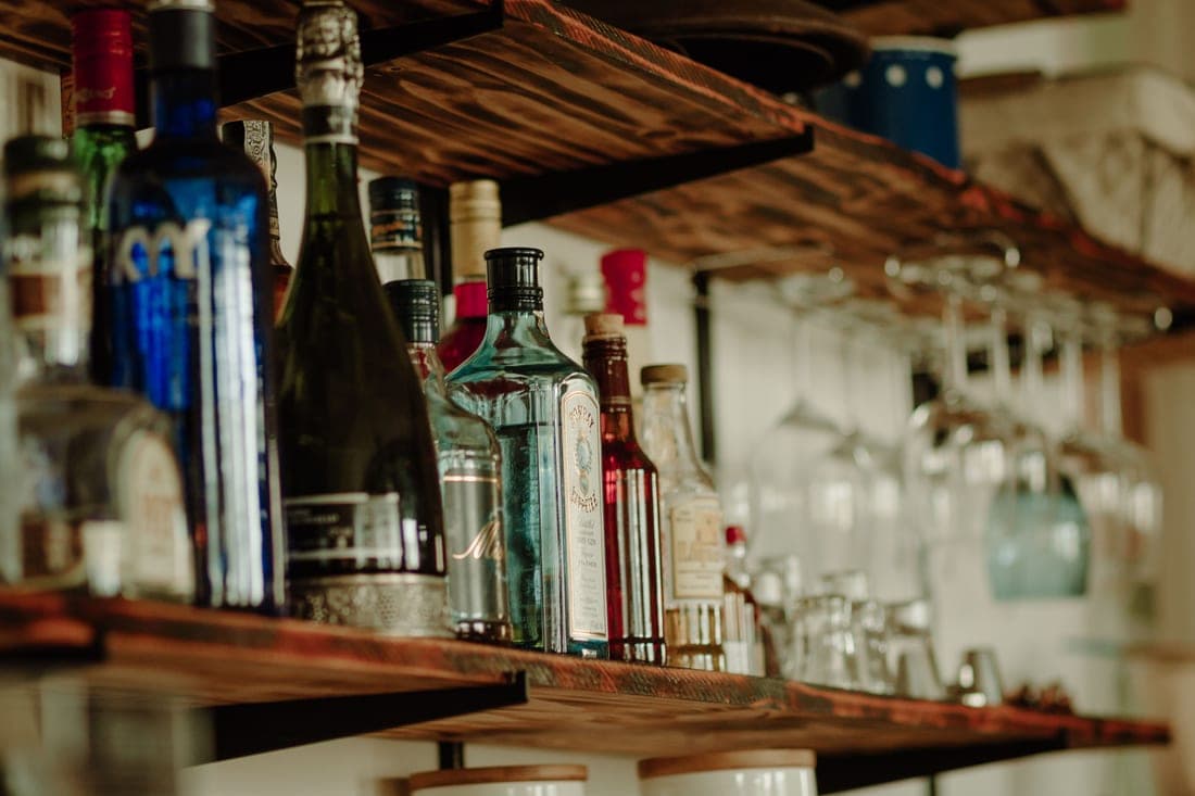A two-tier rolling bar cart holding bottles and glassware