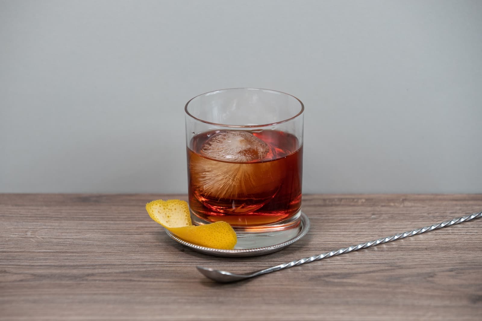 A single clear ice sphere in a heavy rocks glass